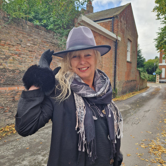 Lady wearing a Grey and Black felt Fedora Hat, Black Gloves with a faux fur cuff and a Black and Grey Scarf with tassels.