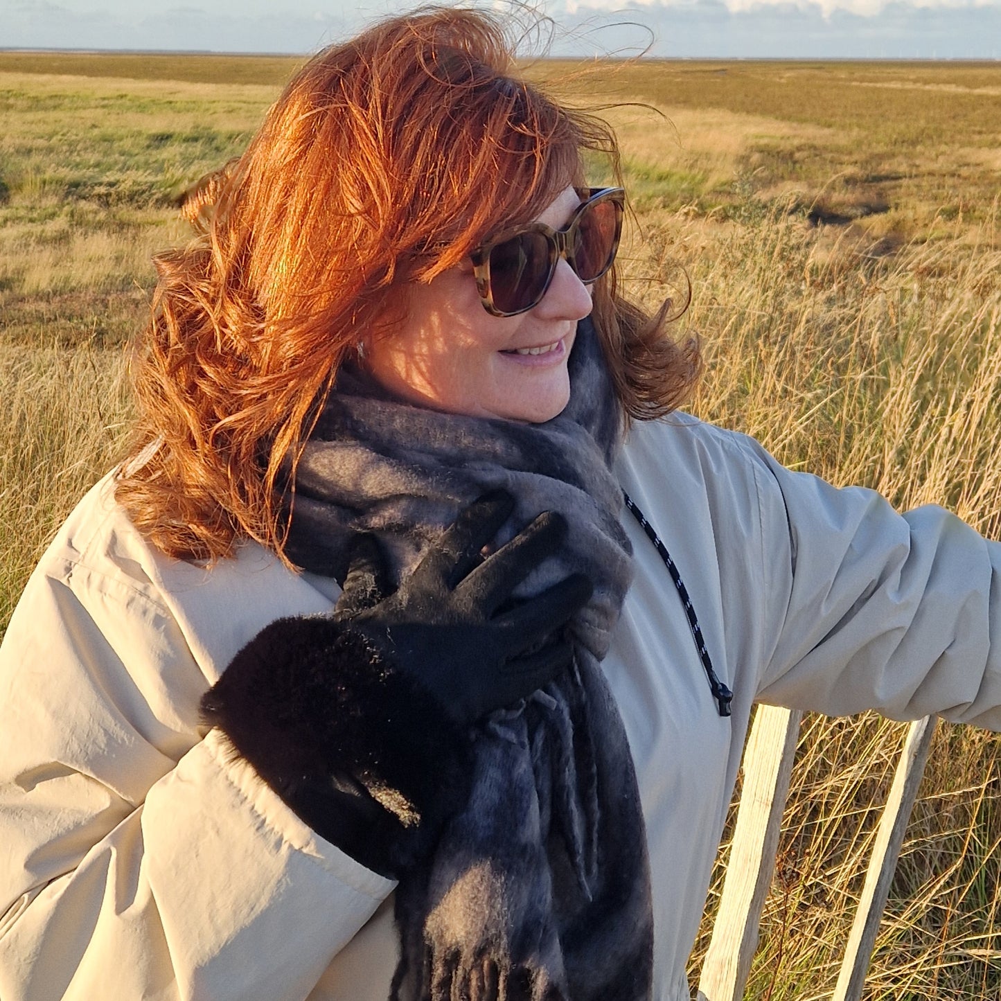 Lady wearing a grey and black zebra print scarf and black gloves with a faux fur cuff.