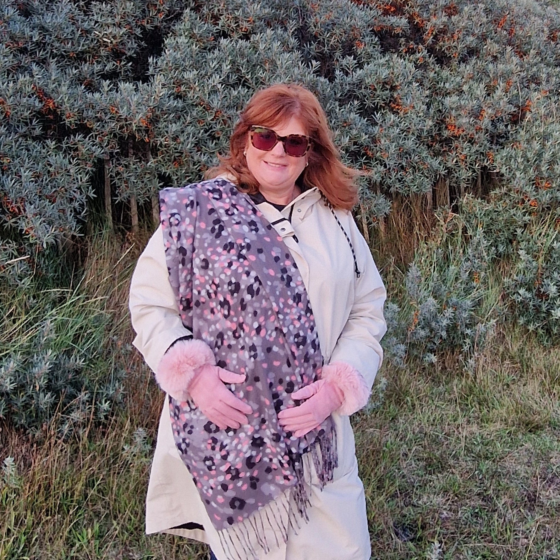 Lady wearing a grey scarf with a leopard print pattern in pink, white and black, with matching pale pink gloves with a faux fur cuff.