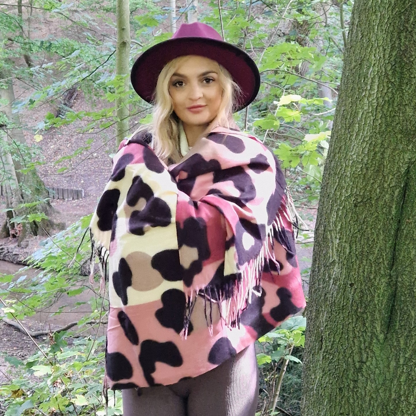 Young woman wearing an abstract leopard print scarf in pink, cream, raspberry and mocha colours with a Fedora hat in Maroon and black.