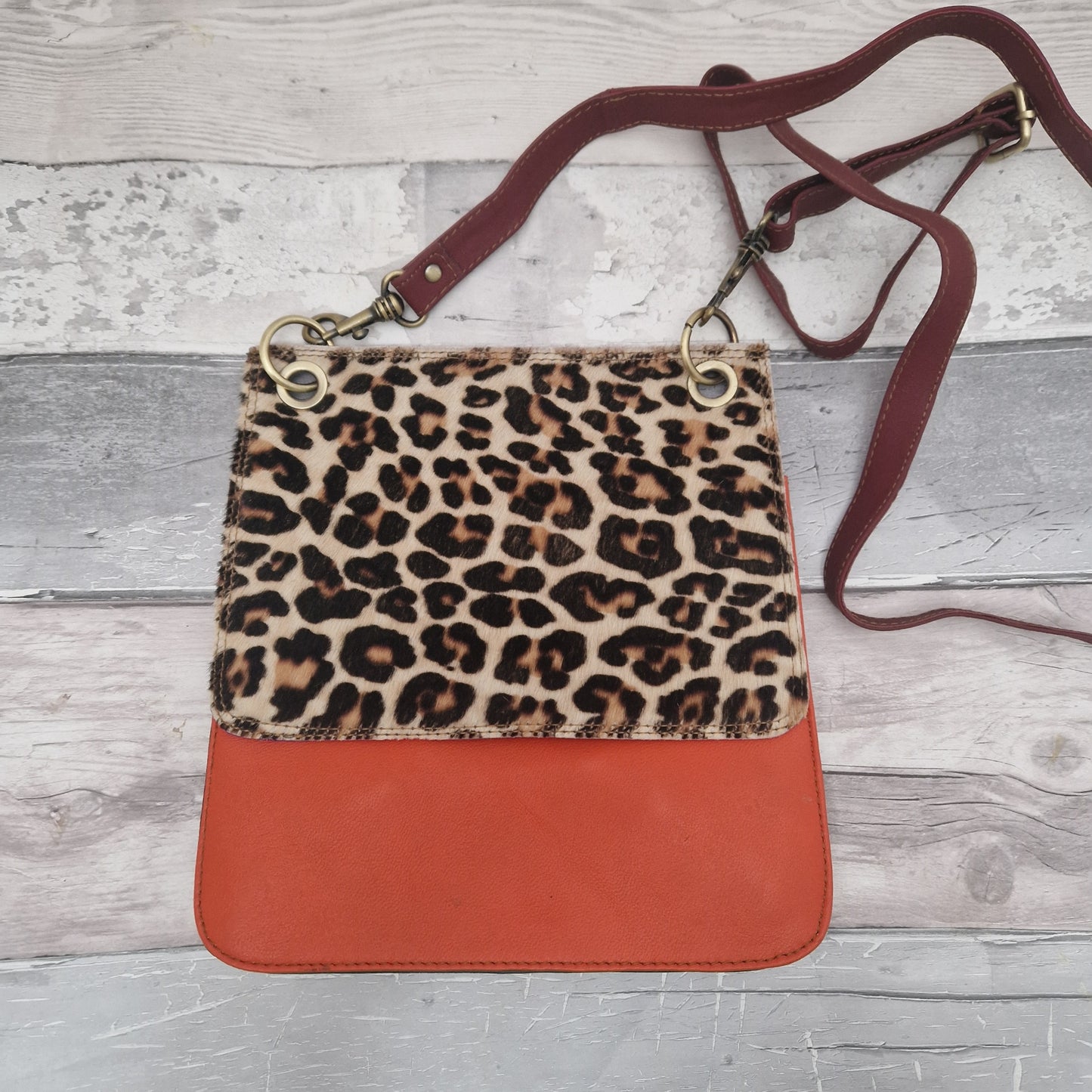 All leather modern messenger style bag with a bright orange panel and textured leopard print panel.