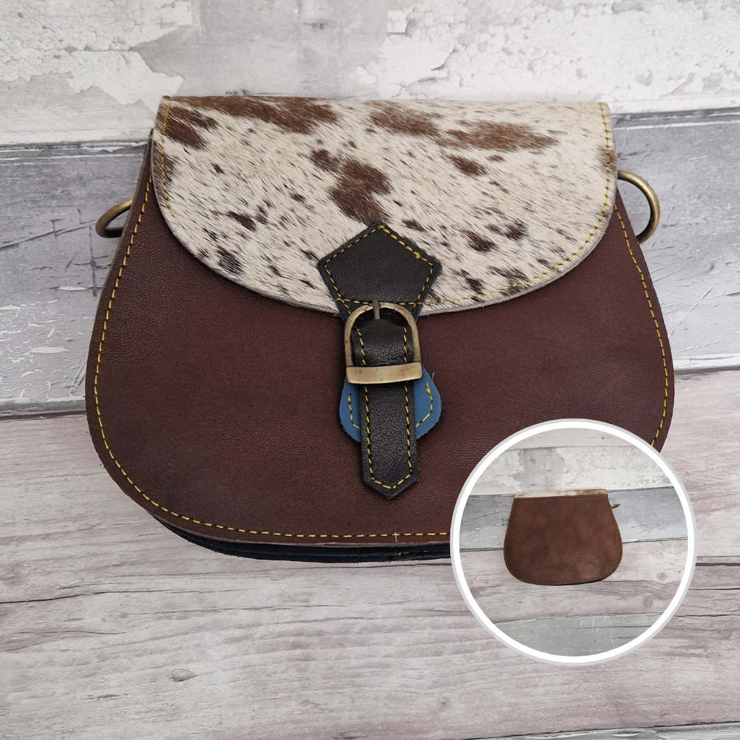 Leather saddlebag shaped bag with a dark brown front and a textured panel of cow print.