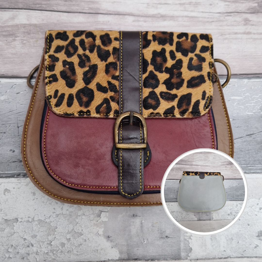 All leather saddlebag style ladies bag in dark red and tan with a textured panel of Jaguar print. Brass buckle closer.