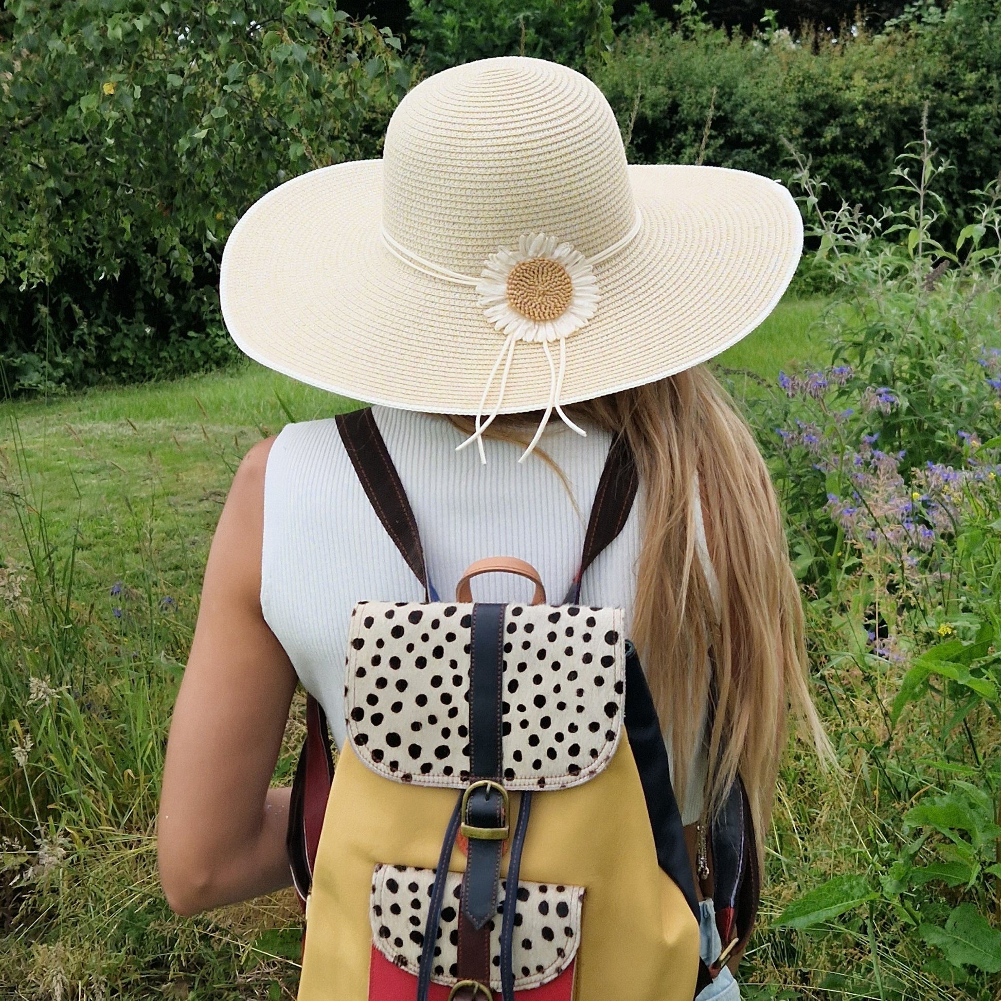 Young woman wearing a wide brimmed hat with a daisy decoration.