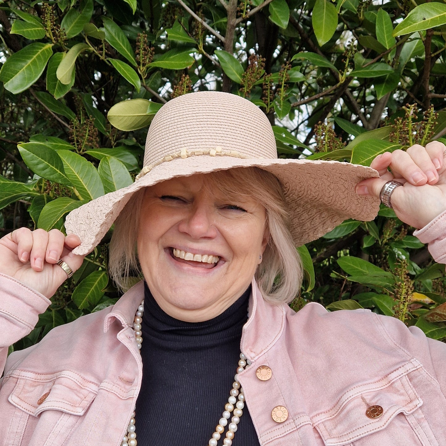 Lady wearing a pale pink wide brimmed sun hat.