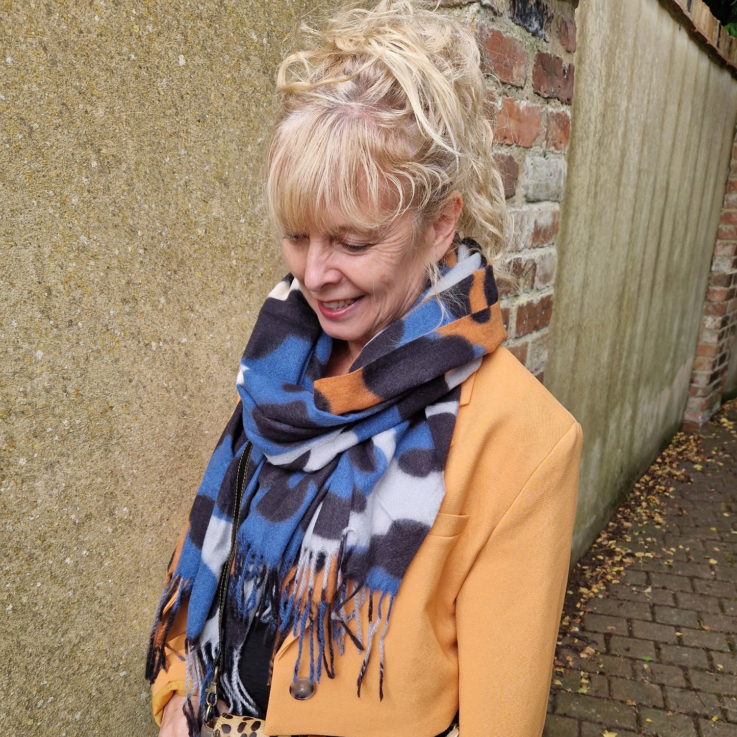 Lady wearing a blue and cream leopard print scarf with black, tan and grey accents.