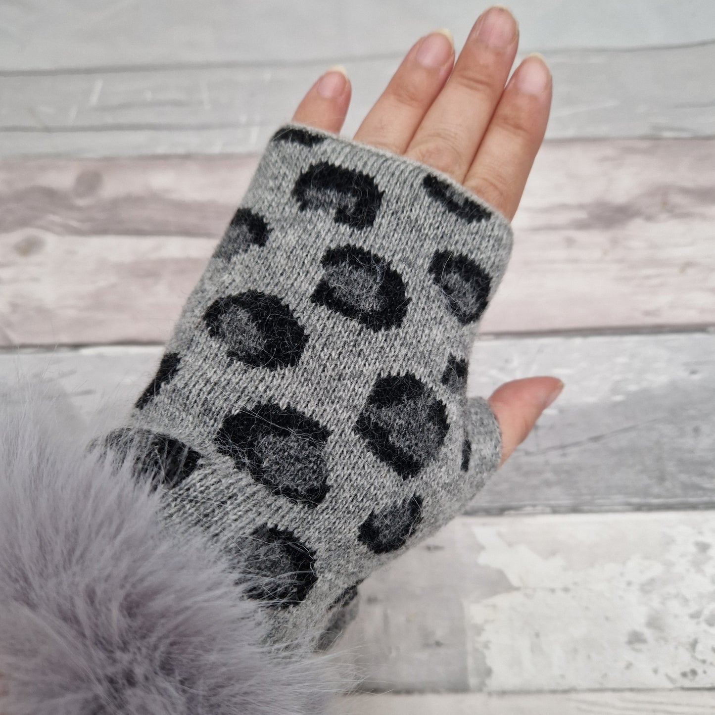 Grey coloured fingerless gloves with a faux fur grey cuff around the wrist and leopard print pattern in dark grey tones.