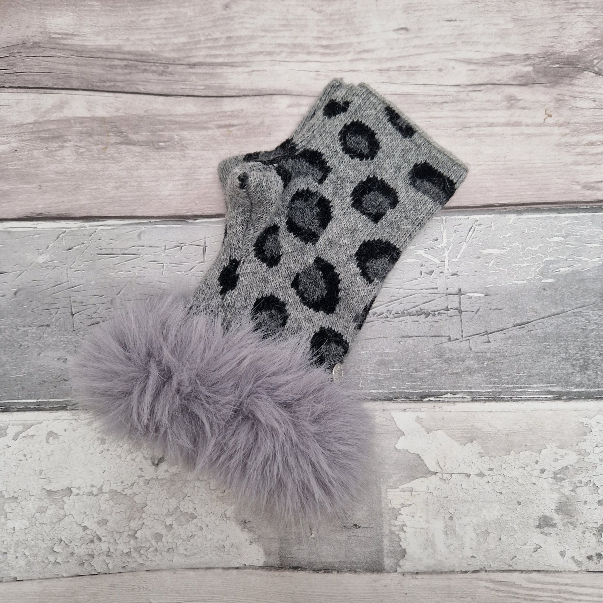 Grey coloured fingerless gloves with a faux fur grey cuff around the wrist and leopard print pattern in dark grey tones.