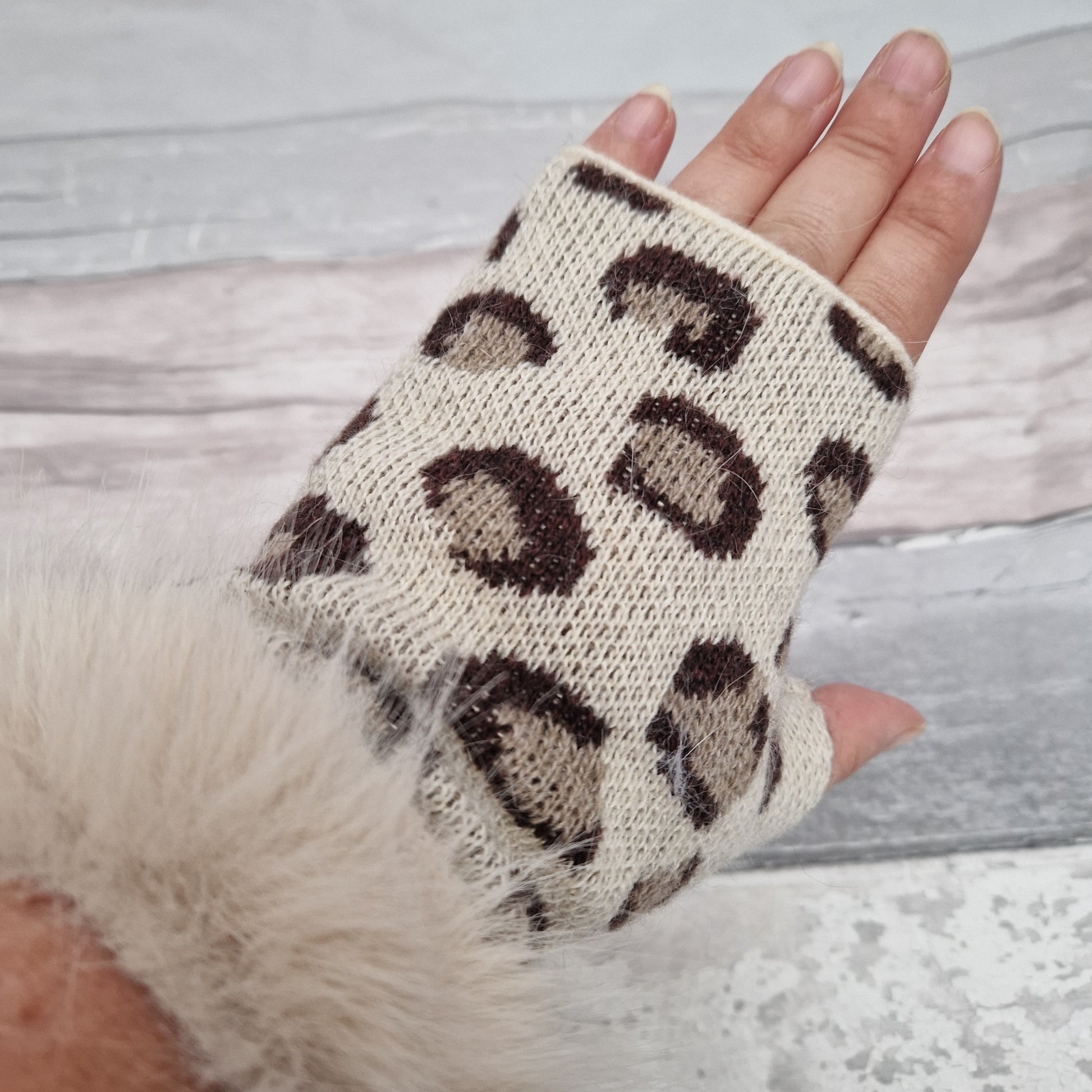 Cream coloured fingerless gloves with a faux fur cream cuff around the wrist and leopard print pattern in warm brown tones.