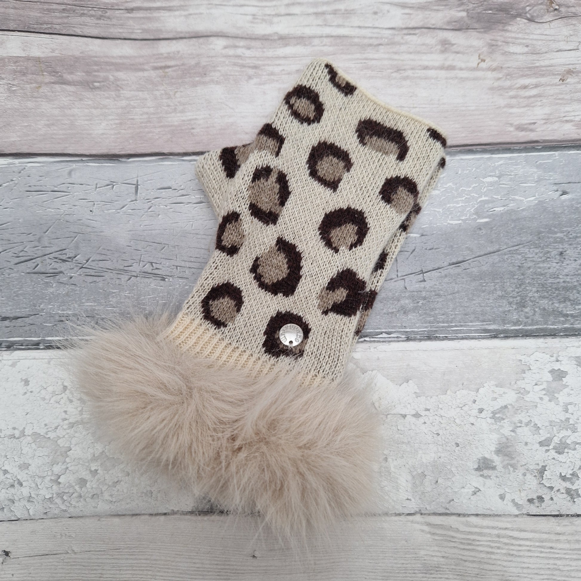 Cream coloured fingerless gloves with a faux fur cream cuff around the wrist and leopard print pattern in warm brown tones.