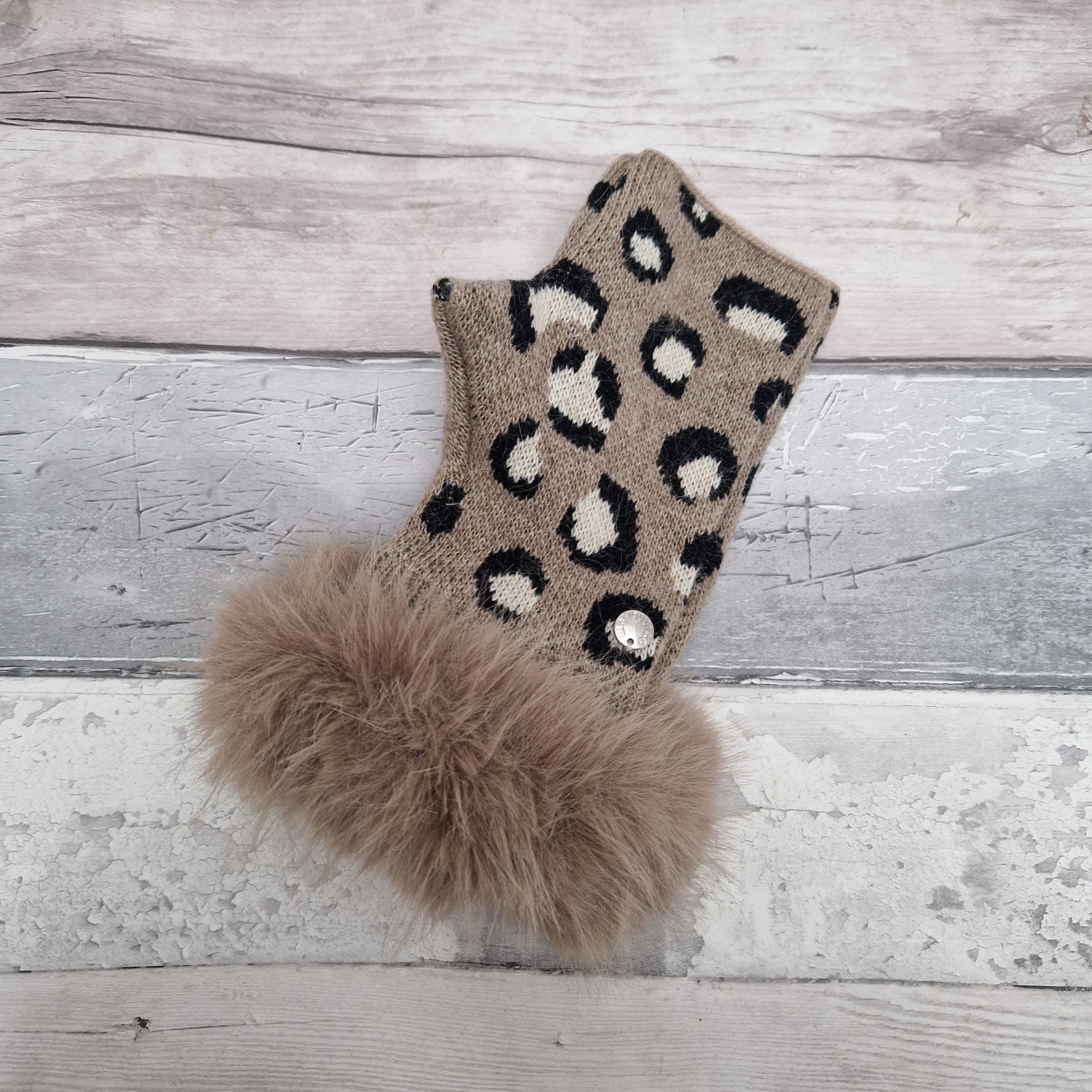 Beige coloured fingerless gloves with a faux fur beige cuff around the wrist and leopard print pattern in cream and black tones.