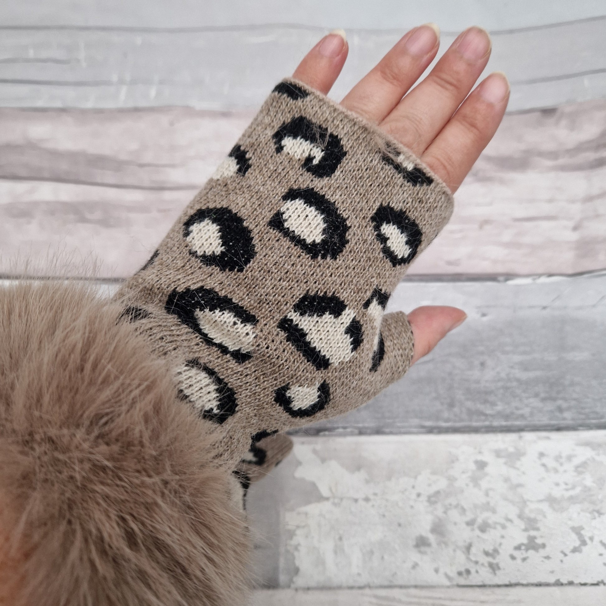 Beige coloured fingerless gloves with a faux fur beige cuff around the wrist and leopard print pattern in cream and black tones.