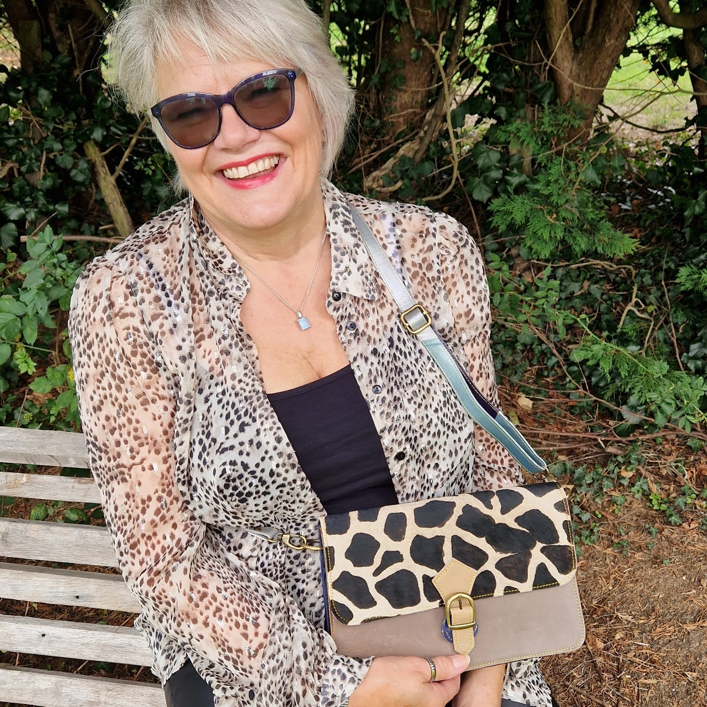 Lady carrying a leather bag in multi colours with panel of textured animal print.