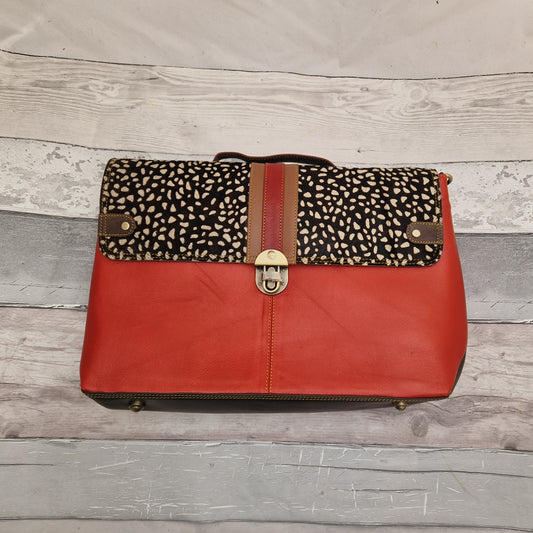 Red Leather satchel style laptop bag with a textured panel in a dark spot. Twist buckle lock.