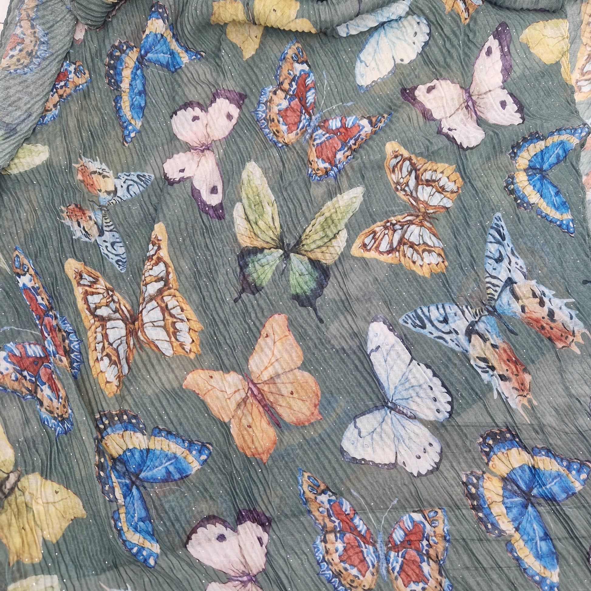 Crinkled textured scarf in green with very pretty collection of butterfly images in different colours.