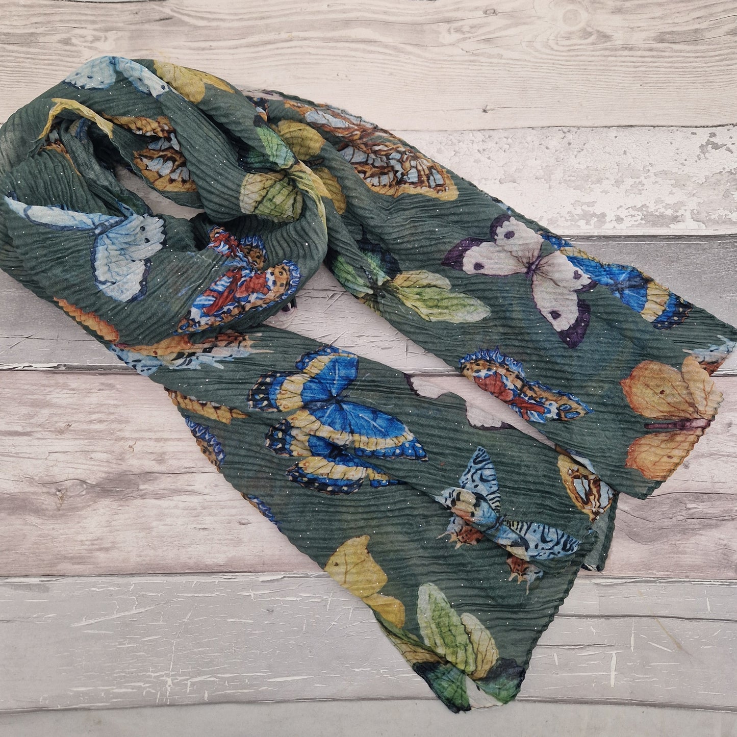 Crinkled textured scarf in green with very pretty collection of butterfly images in different colours.