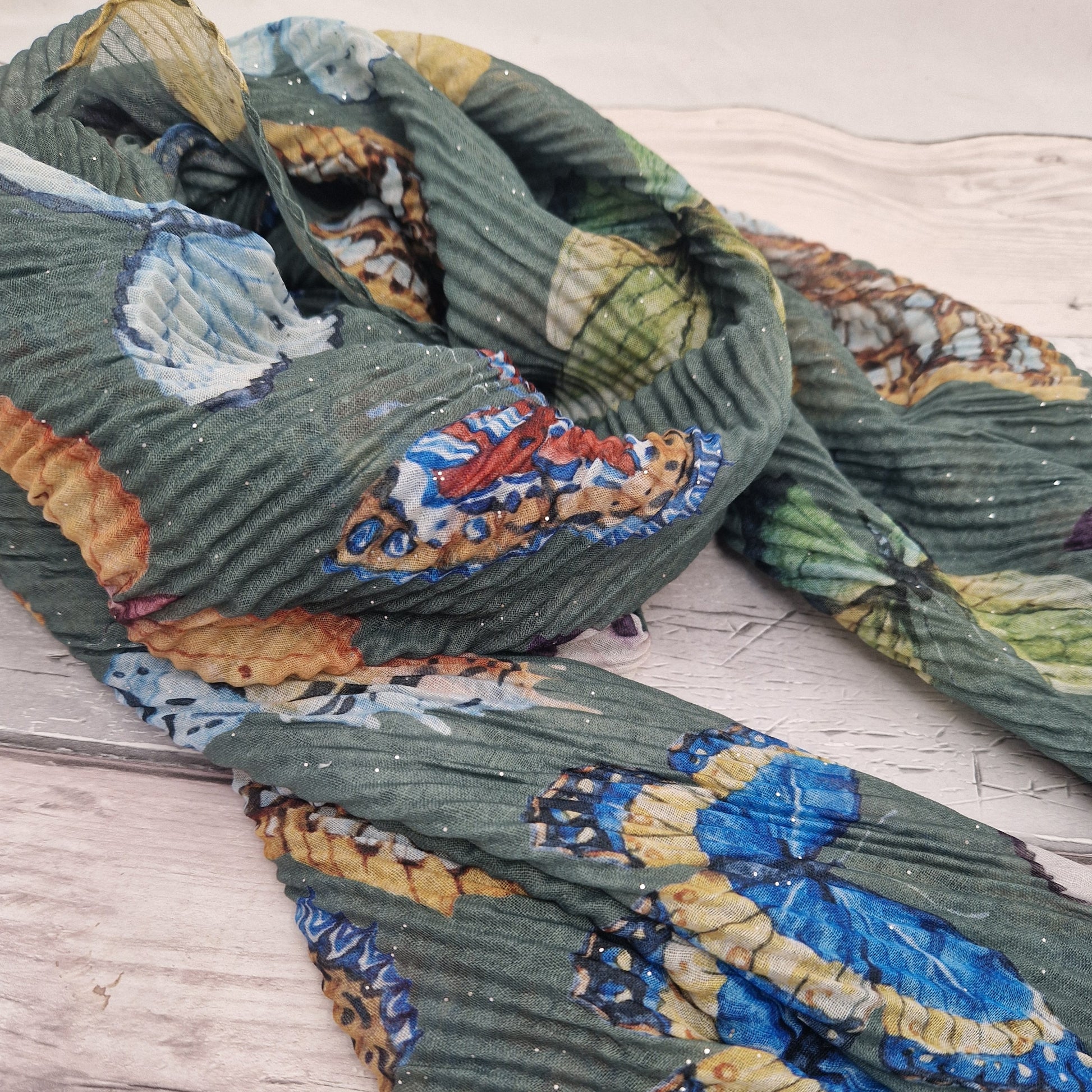 Crinkled textured scarf in green with very pretty collection of butterfly images in different colours.