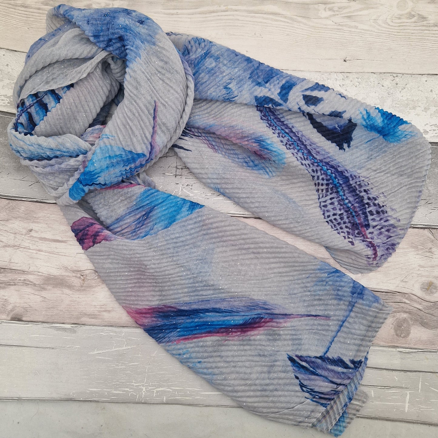 Crinkle effect pale grey scarf decorated with feathers in blue, navy and hot pink.