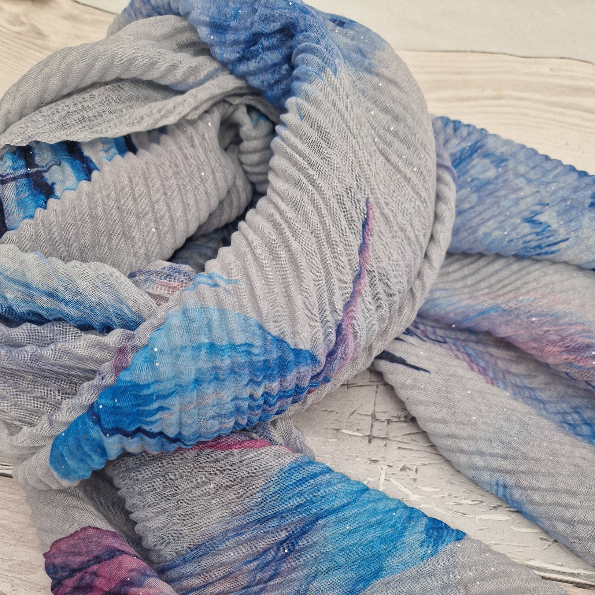 Crinkle effect pale grey scarf decorated with feathers in blue, navy and hot pink.