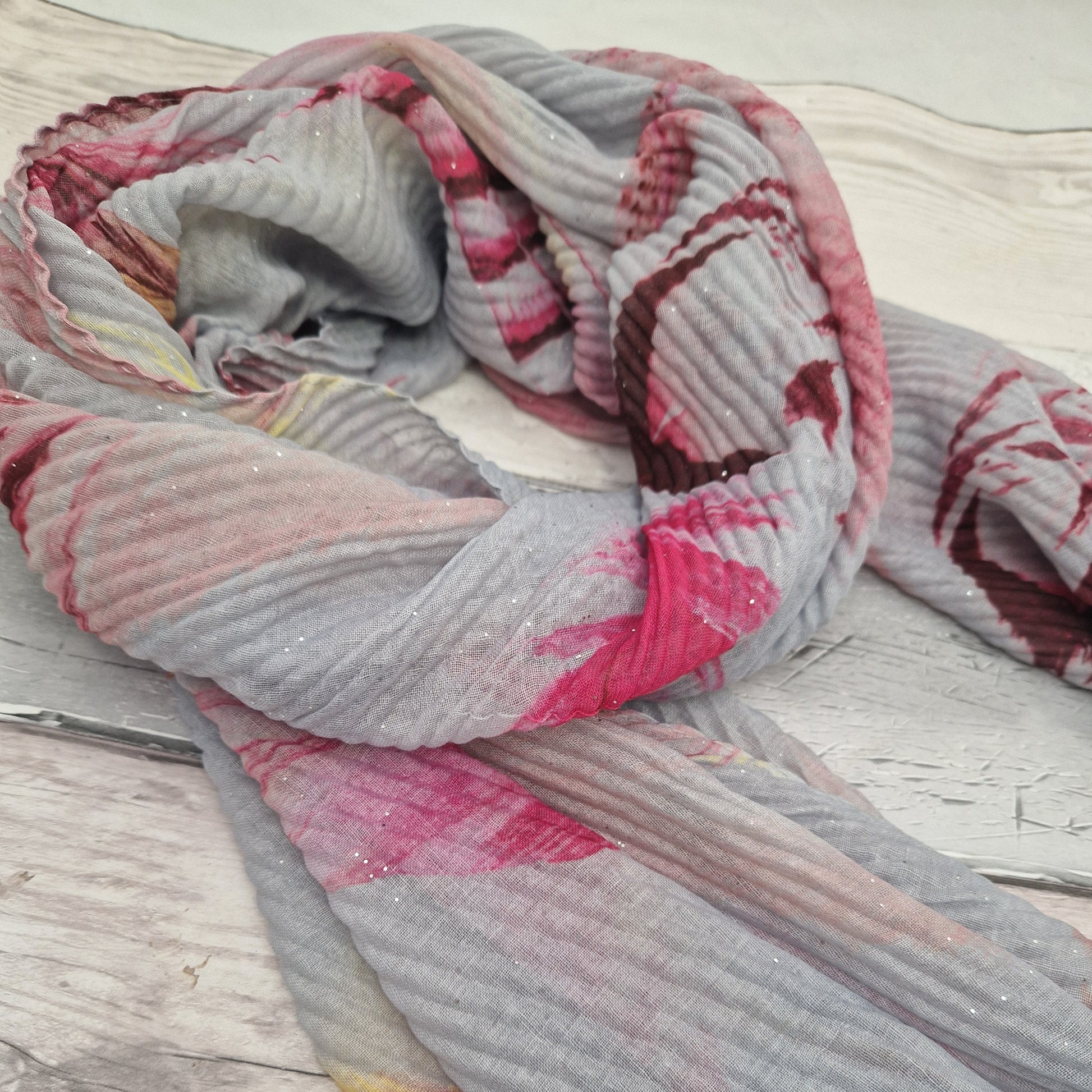 Crinkle effect pale grey scarf decorated with feathers in yellow, baby pink and hot pink.