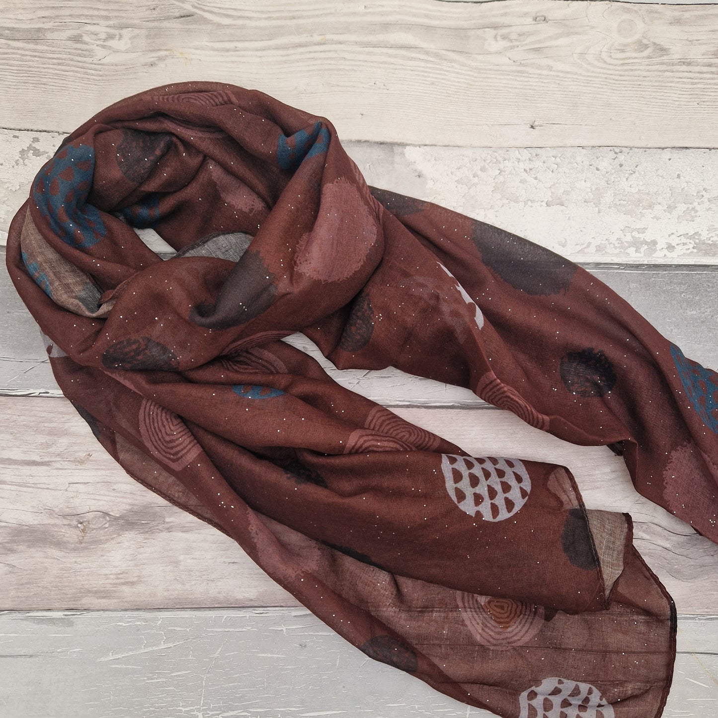 Brown coloured scarf decorated with abstract circles in contrasting colours.