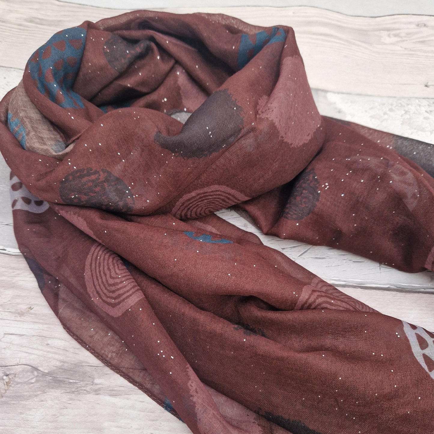 Brown coloured scarf decorated with abstract circles in contrasting colours.