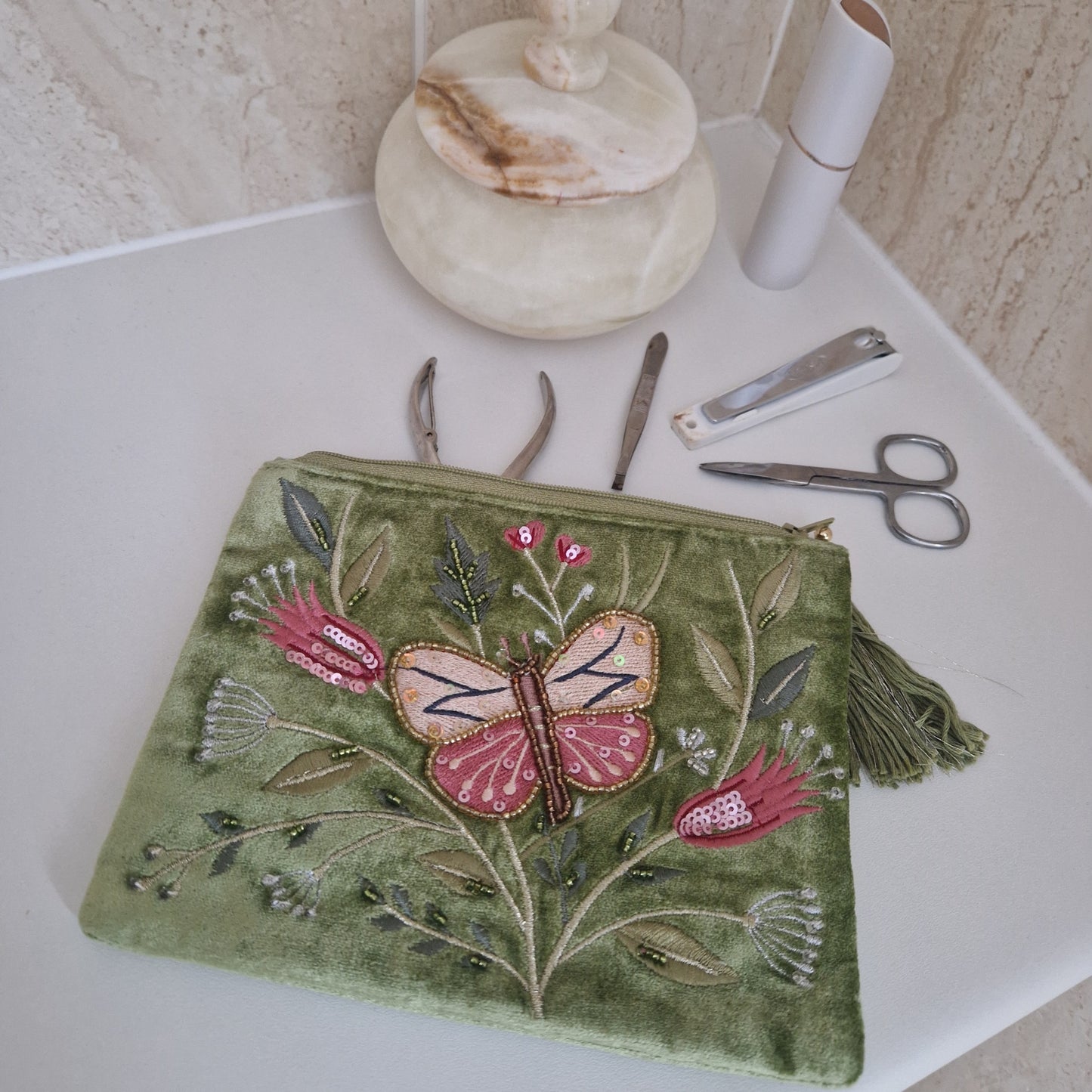 Green velvet pouch with hand embroidered relief featuring a large butterfly amongst matching pink flowers.