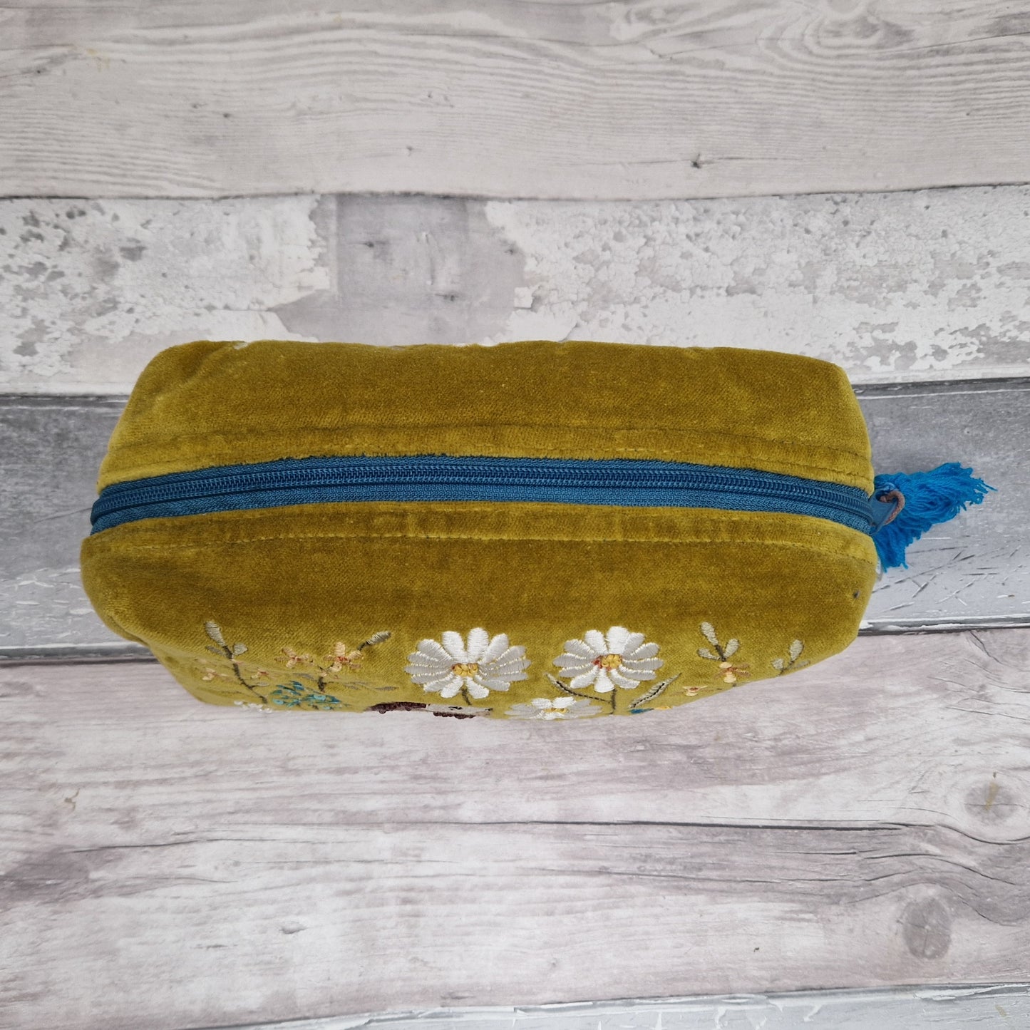 Top down view of a mustard coloured velvet wash bag.