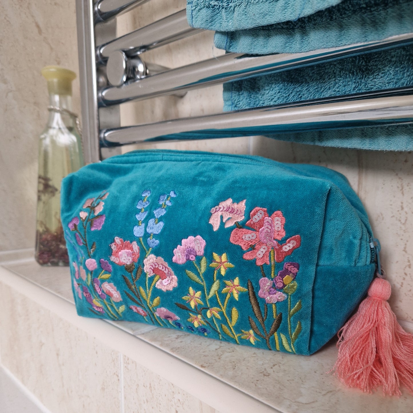 Turquoise coloured velvet wash bag. Hand decorated with embroidery and sequins. Depicting a garden of pretty pink and purple flowers.