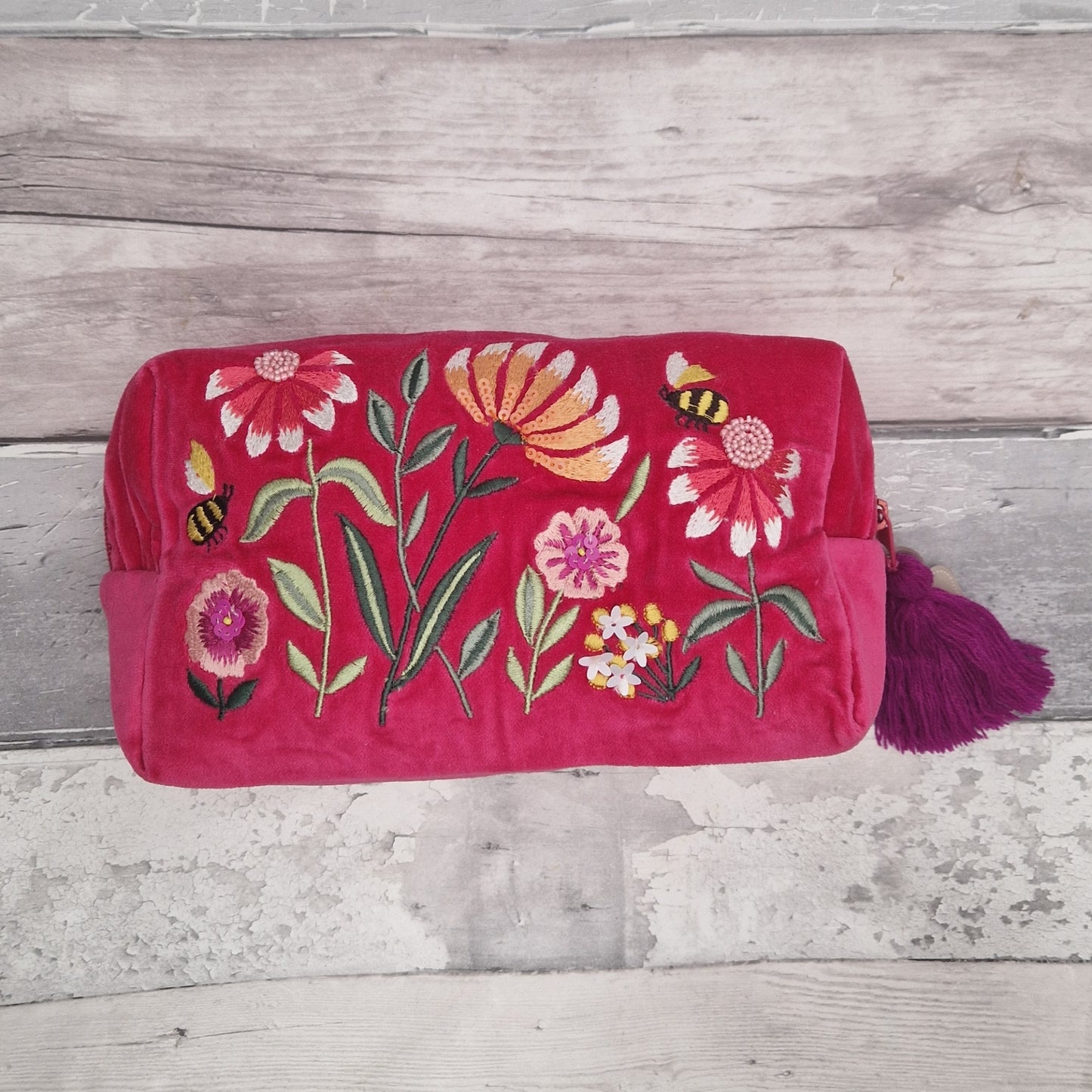 A hot pink velvet washbag. Decorated with embroidery, hand sewn sequins and beads. Depicting a flower garden with bumble bees. 