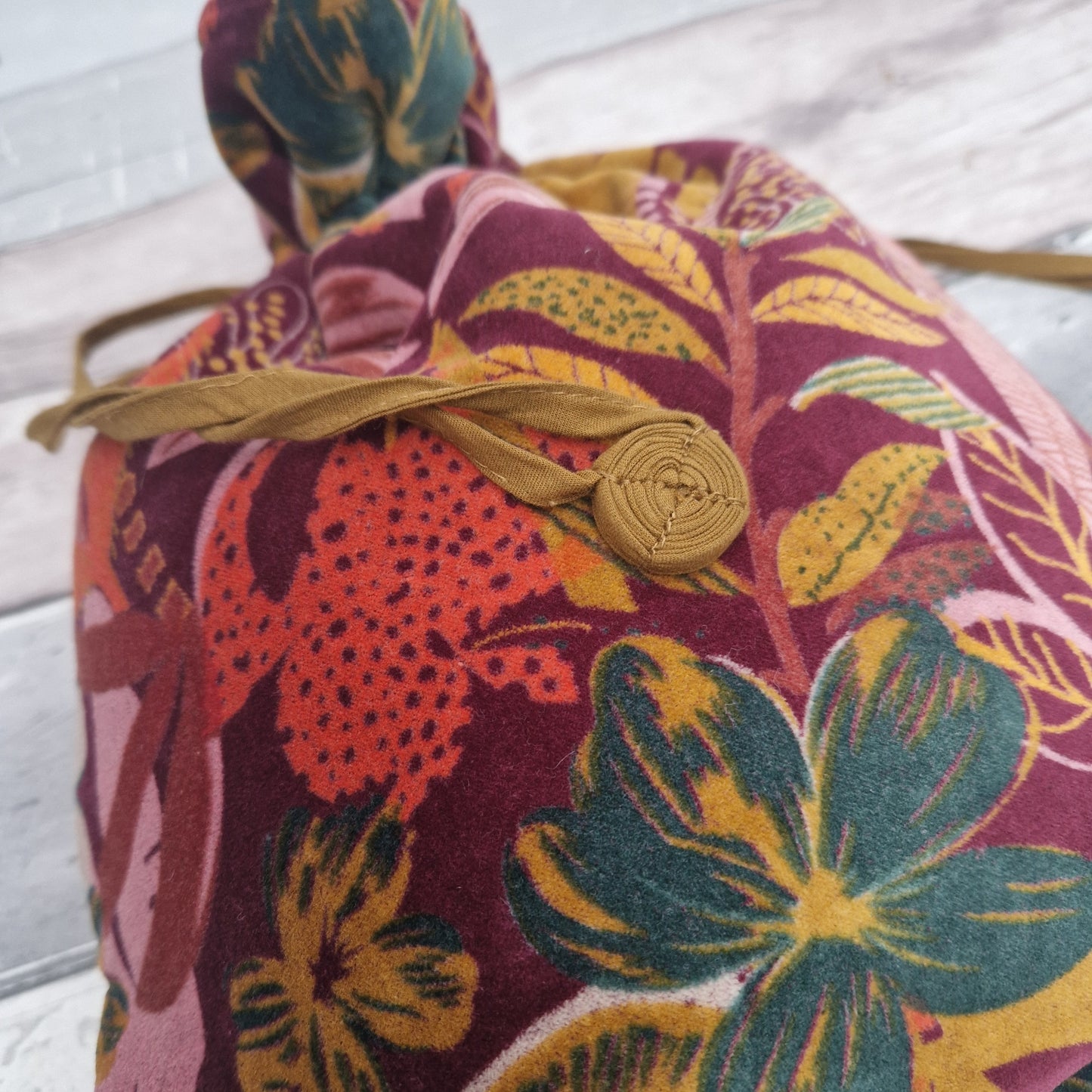 Large drawstring velvet pouch decorated in rich colours depicting a tropical flower garden.