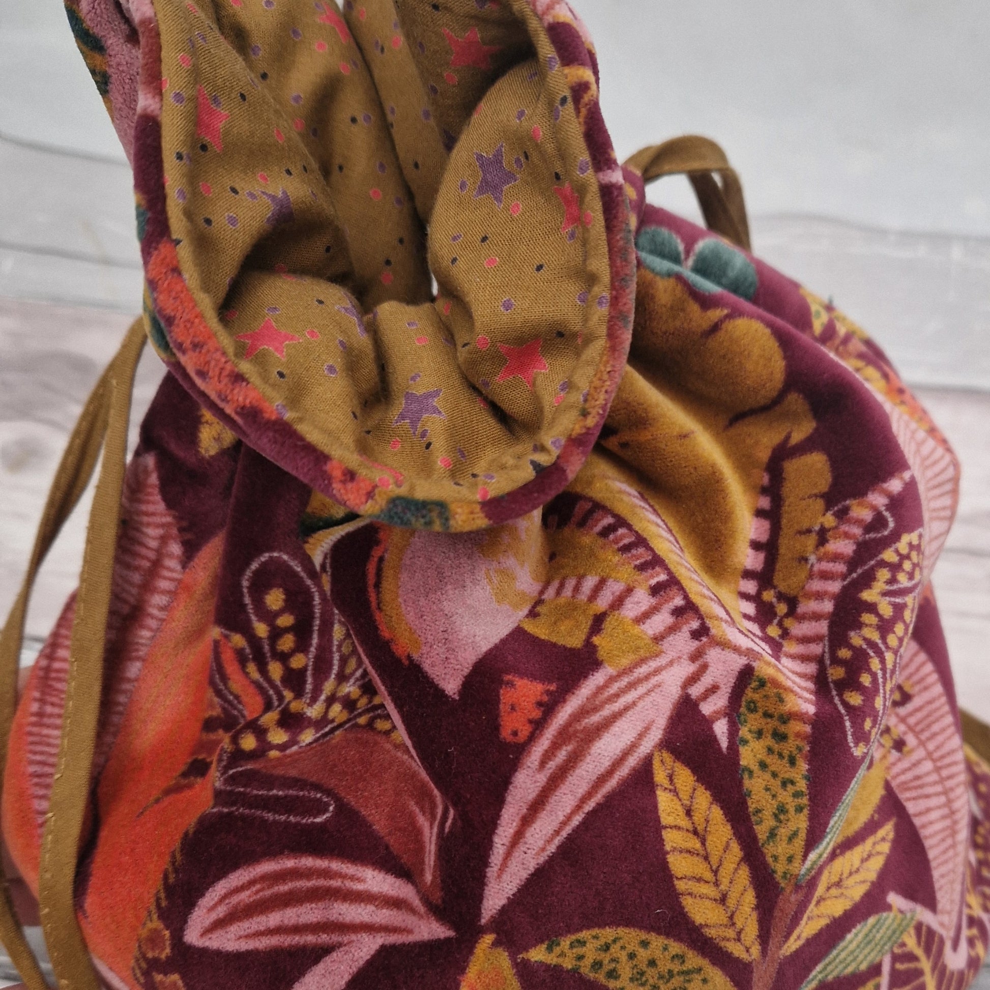 Large drawstring velvet pouch decorated in rich colours depicting a tropical flower garden.