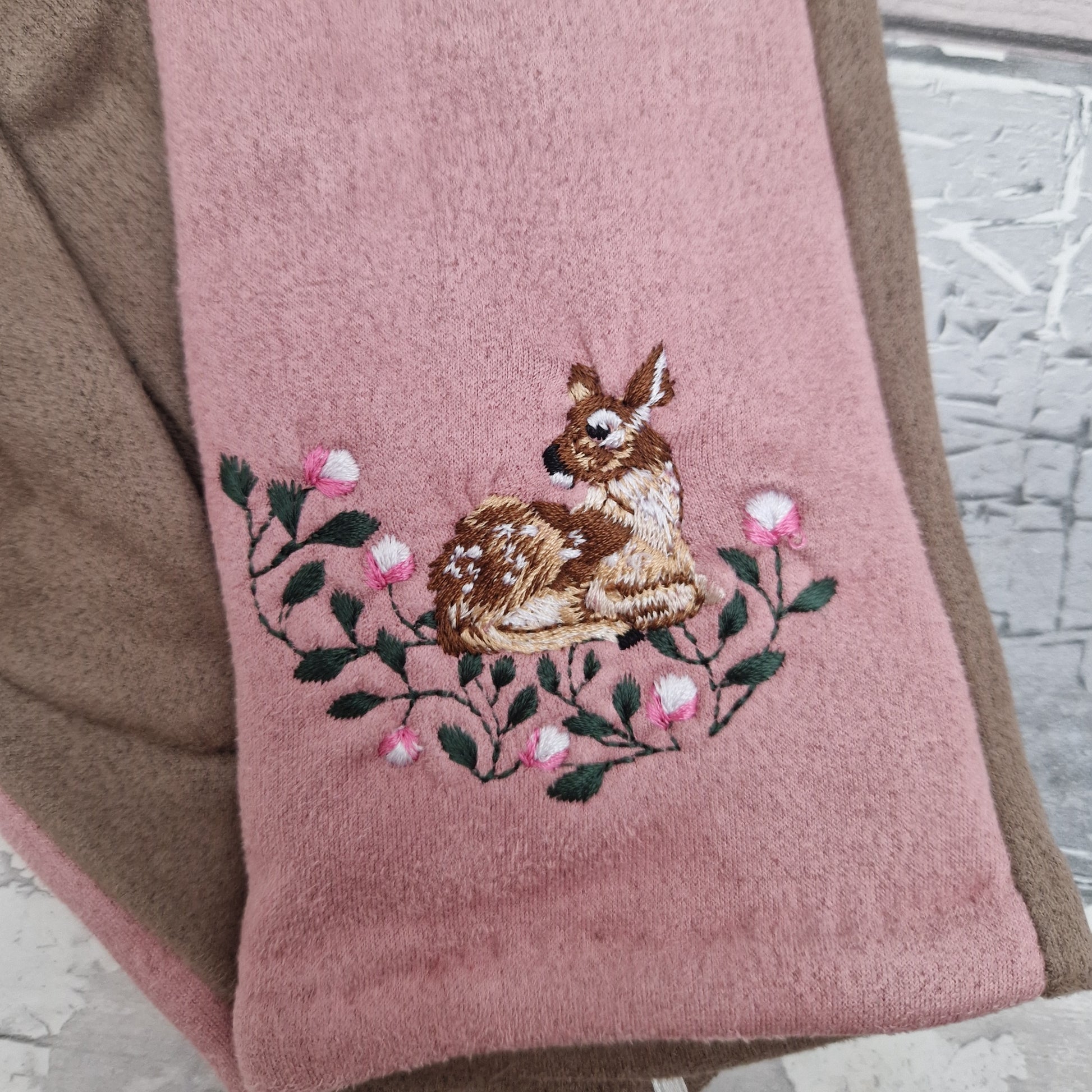 Pink and beige gloves with an embroidered Deer motif on the back of the hand.