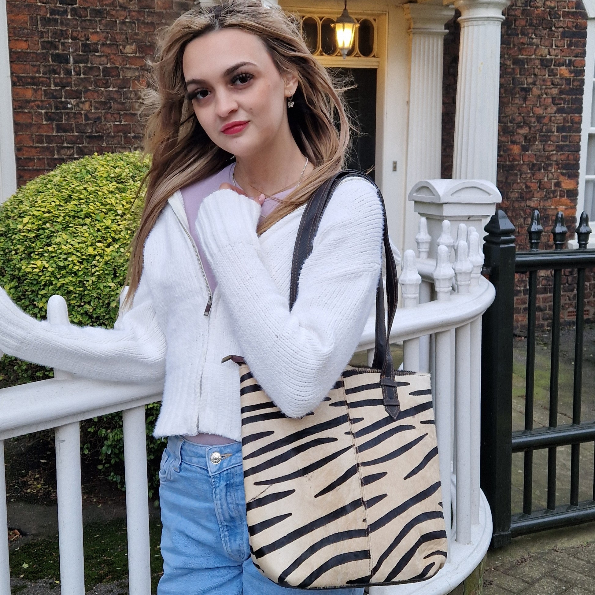 Young woman carrying a zebra tote bag with long black handles.