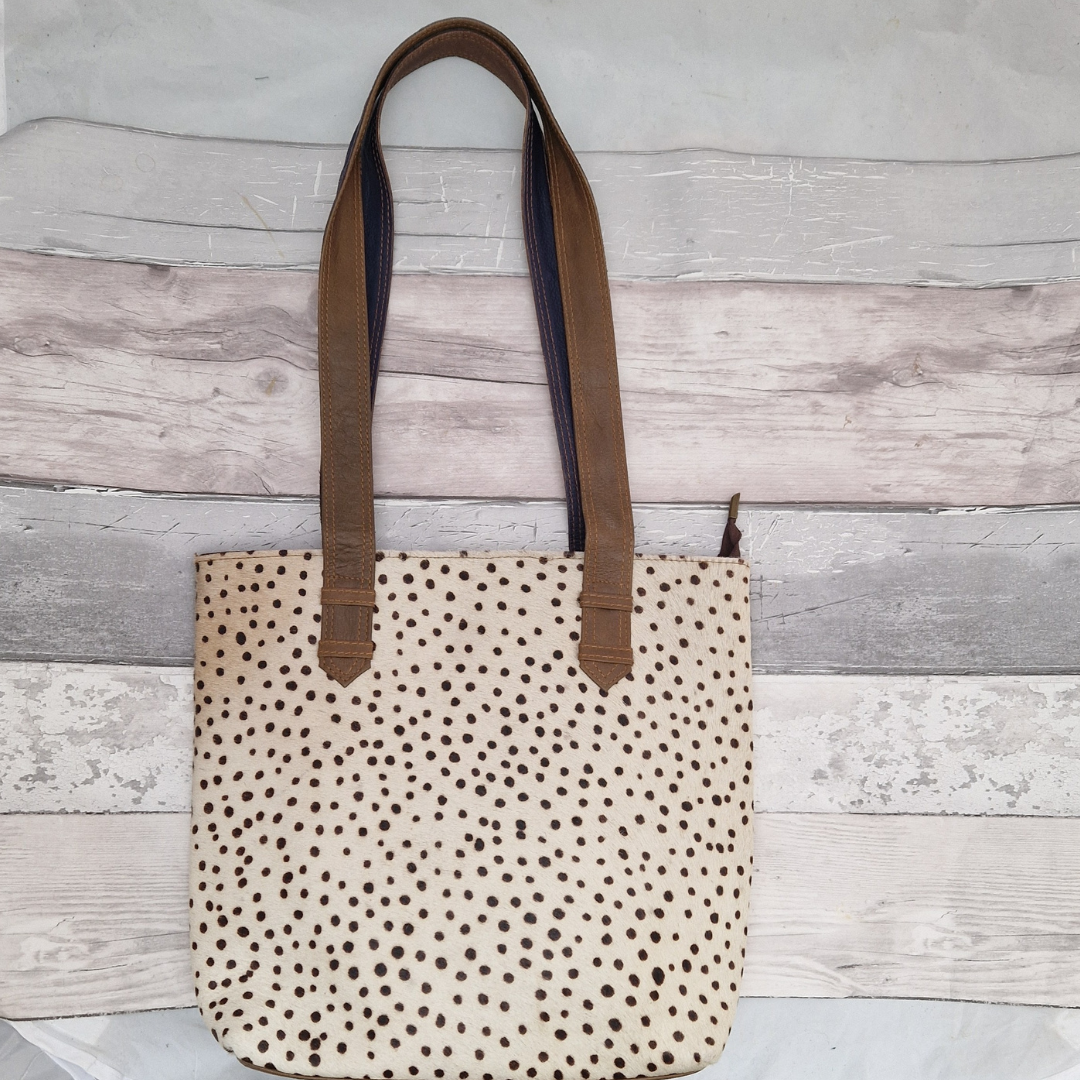 All leather tote bag made with textured panels decorated in spot print. Long handles in brown leather.