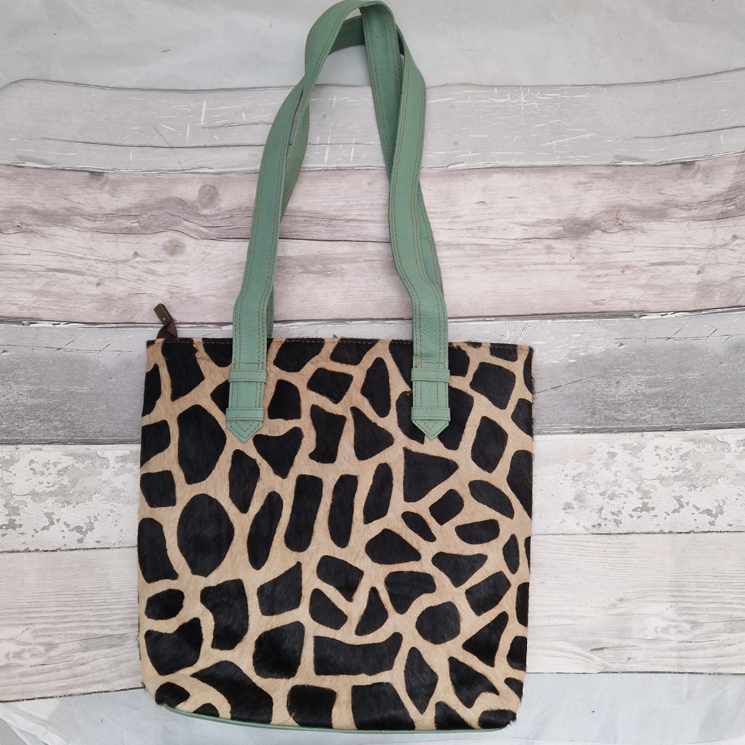 All leather tote bag made with textured panels decorated in Giraffe print. Long handles in aqua blue leather.