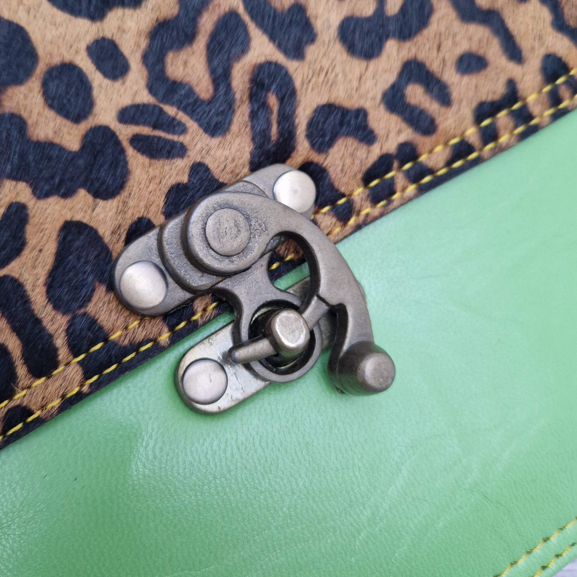 All leather bright green coloured bag with a textured panel of jaguar animal print. A brass swivel clasp secured the bag at the front.