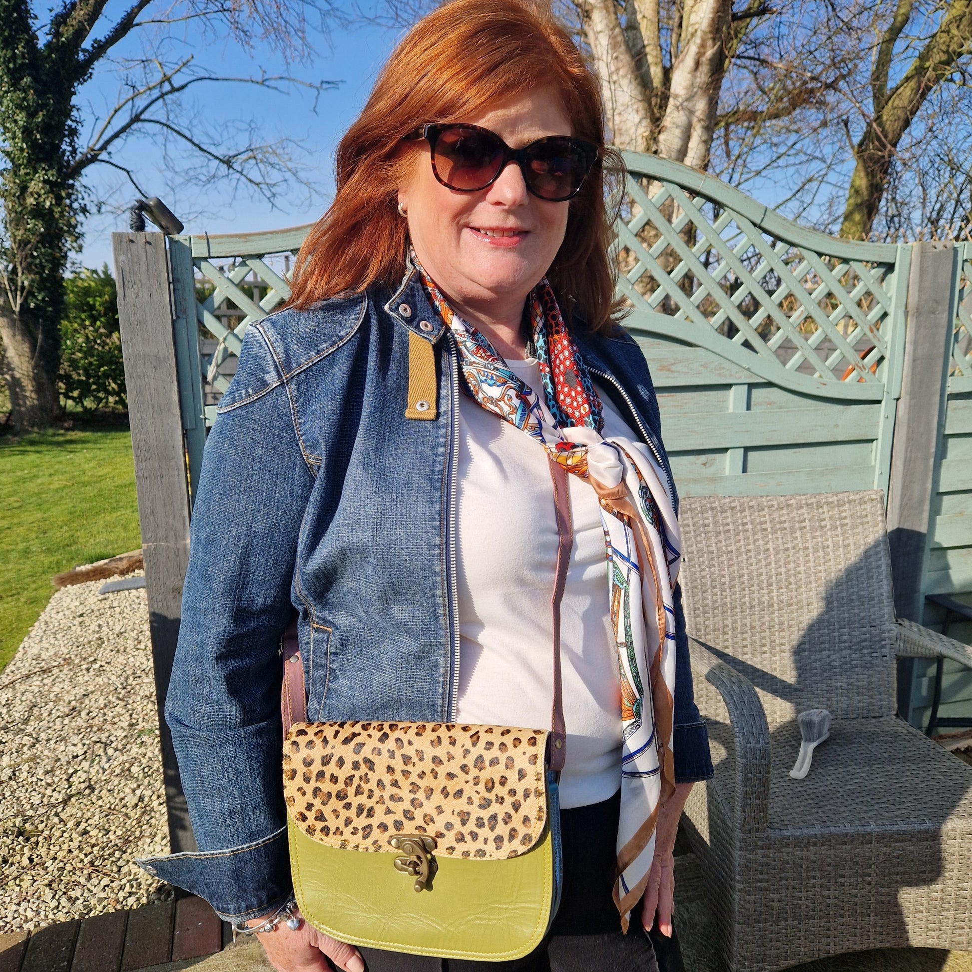 Lady wearing a green crossbody bag with a leopard print panel and a swivel clasp.