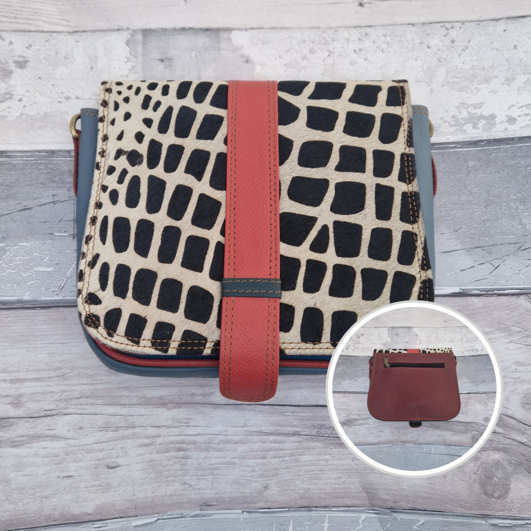 Zoya is a Messenger style bag with a tab on the front to lift for access. She is made from leather off-cuts and is presented in a multitude of colours finished with a large front panel in textured giraffe animal print.